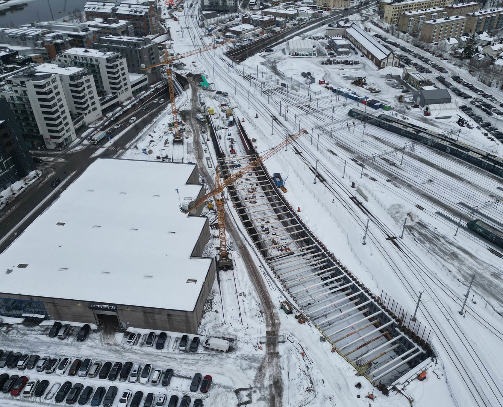  Byggeplass nær togspor med kraner og snø.