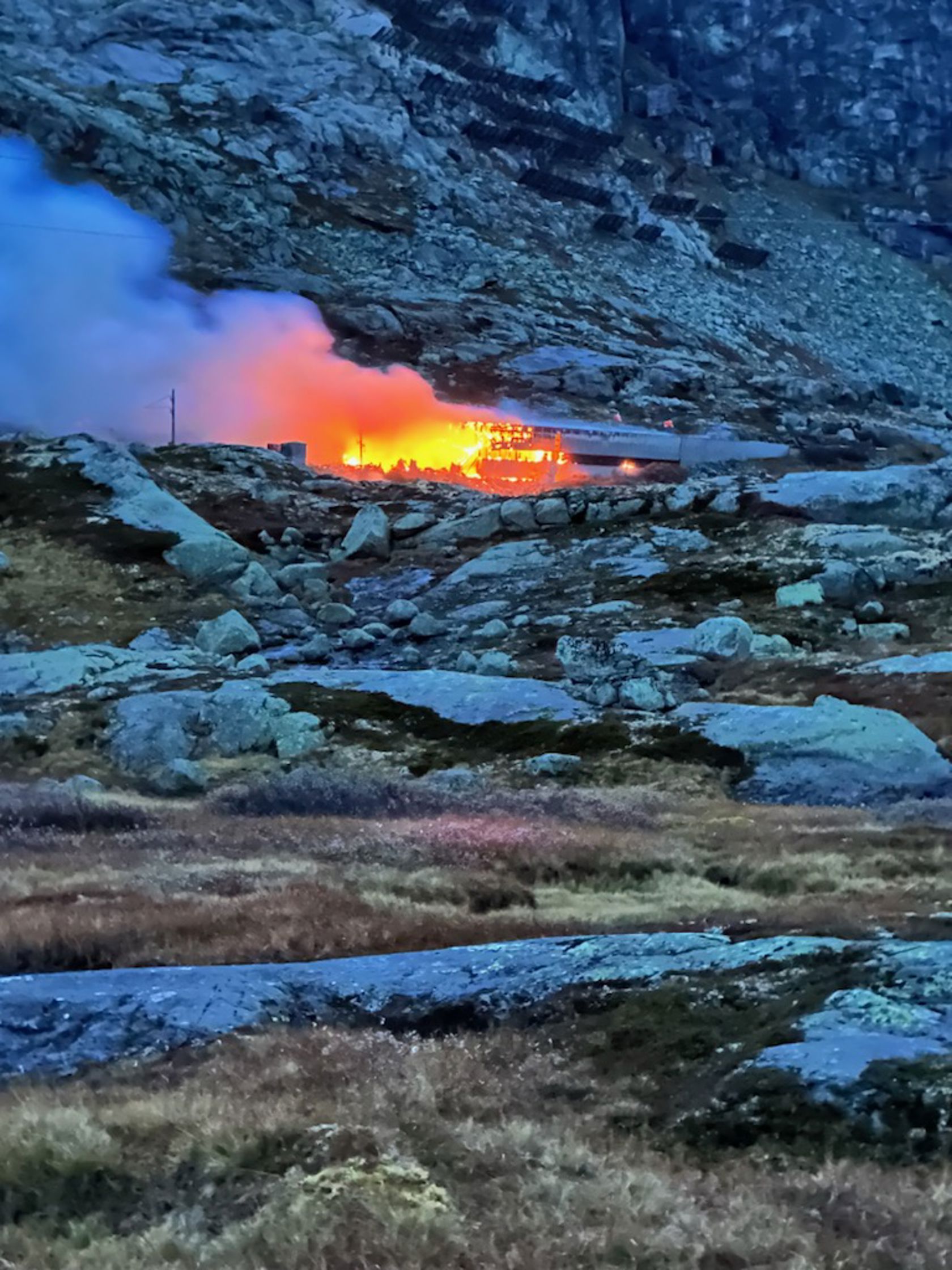 Rødgule flammer fra brann i bygning på fjellet