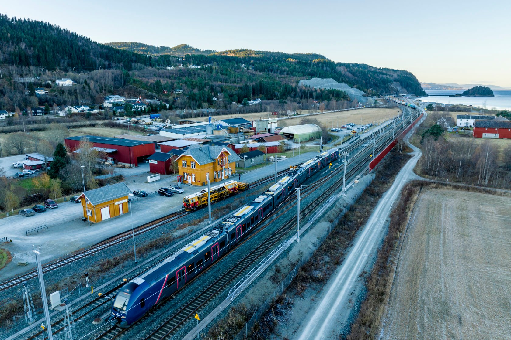 Bilde av Hell stasjon med passasjertog foran stasjonsbygningen.