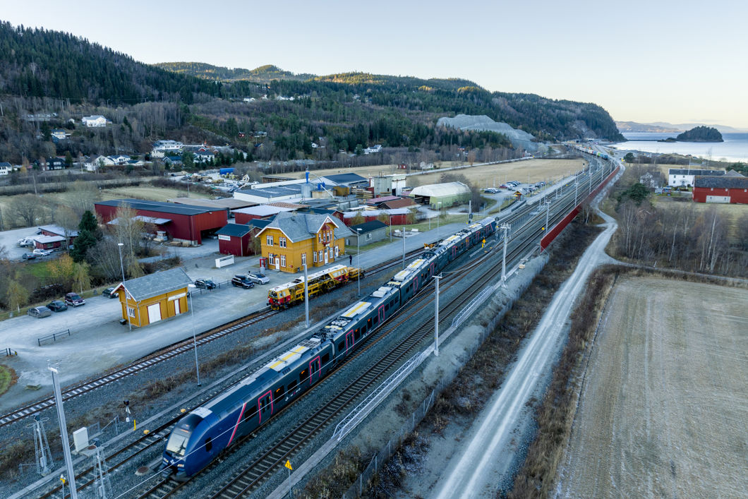 Bilde av Hell stasjon med passasjertog foran stasjonsbygningen.