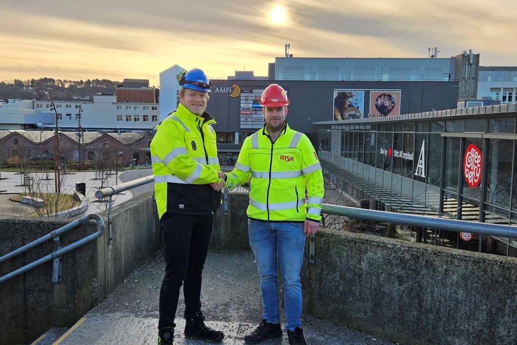 To menn i gul jakke med hjelm som tar hverandre i hånda 