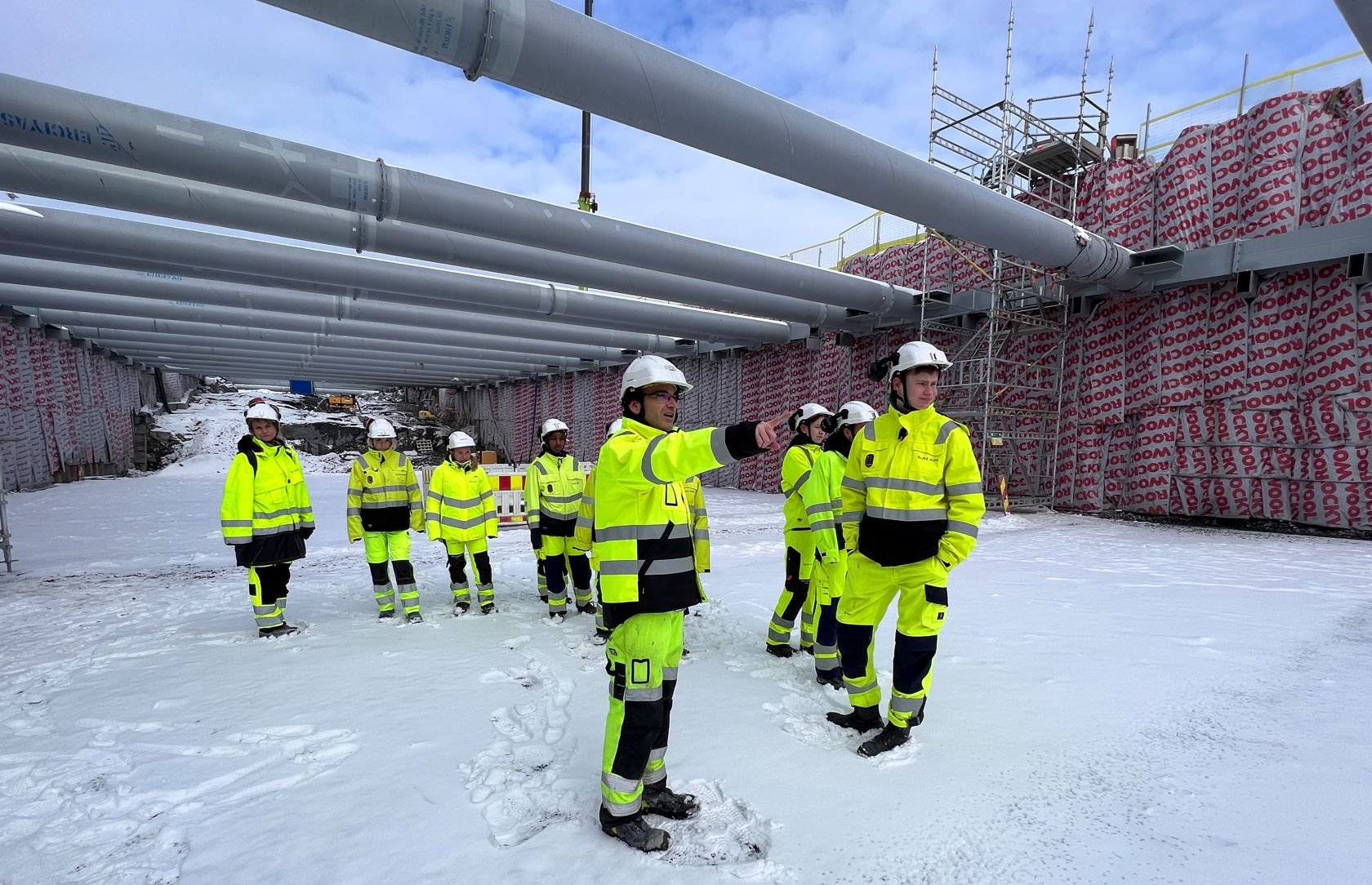 Menn og kvinner i verneutstyr står i snødekt kulvert. I bakgrunnen sees avstivere og spuntvegg.