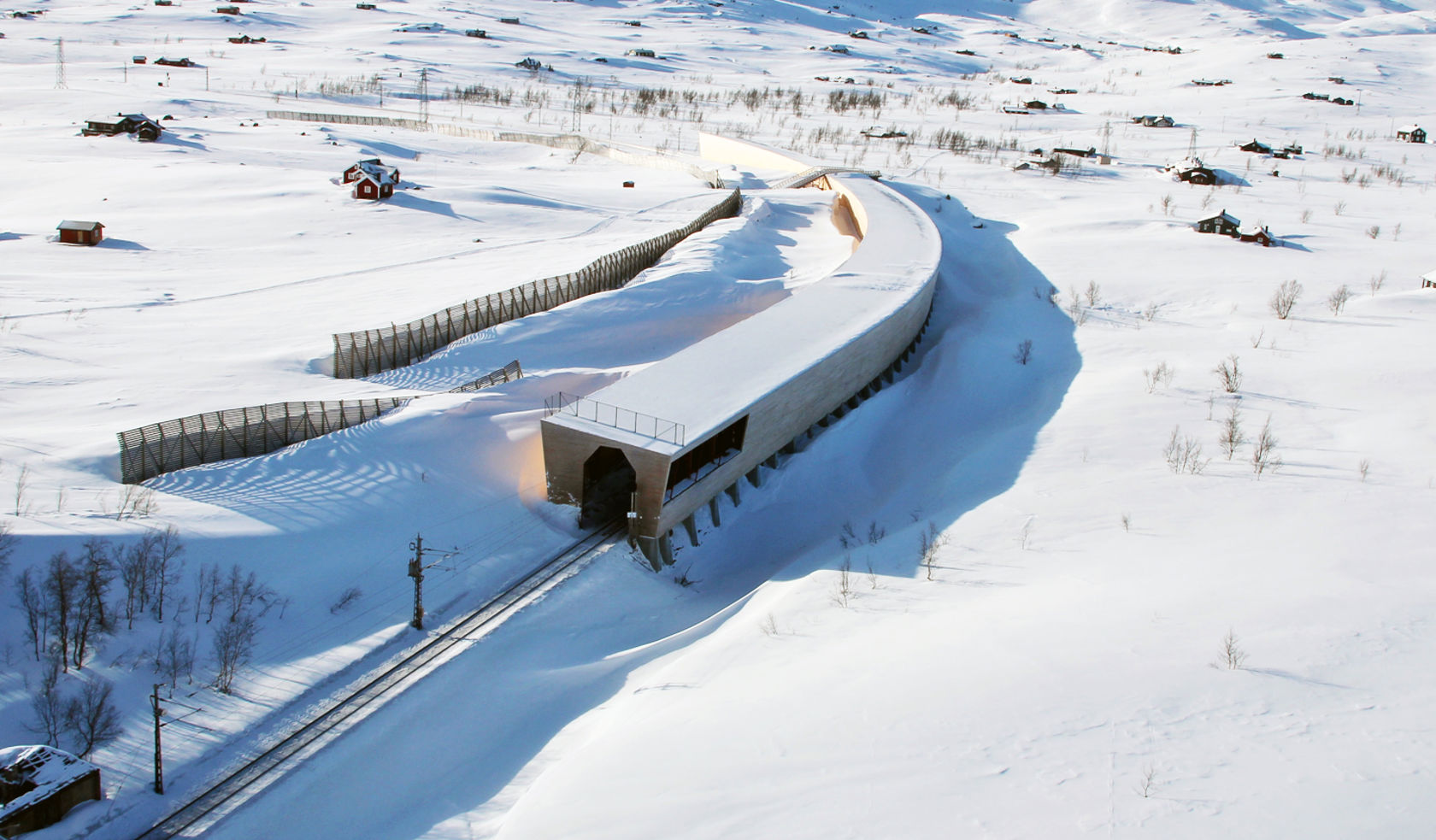 Snøoverbygg over skinnegangen i snødekt terreng.