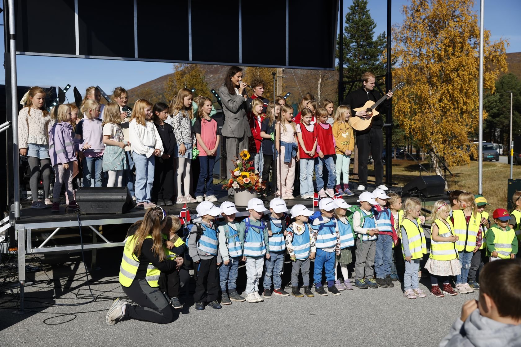 Voksne og barn synger på en scene