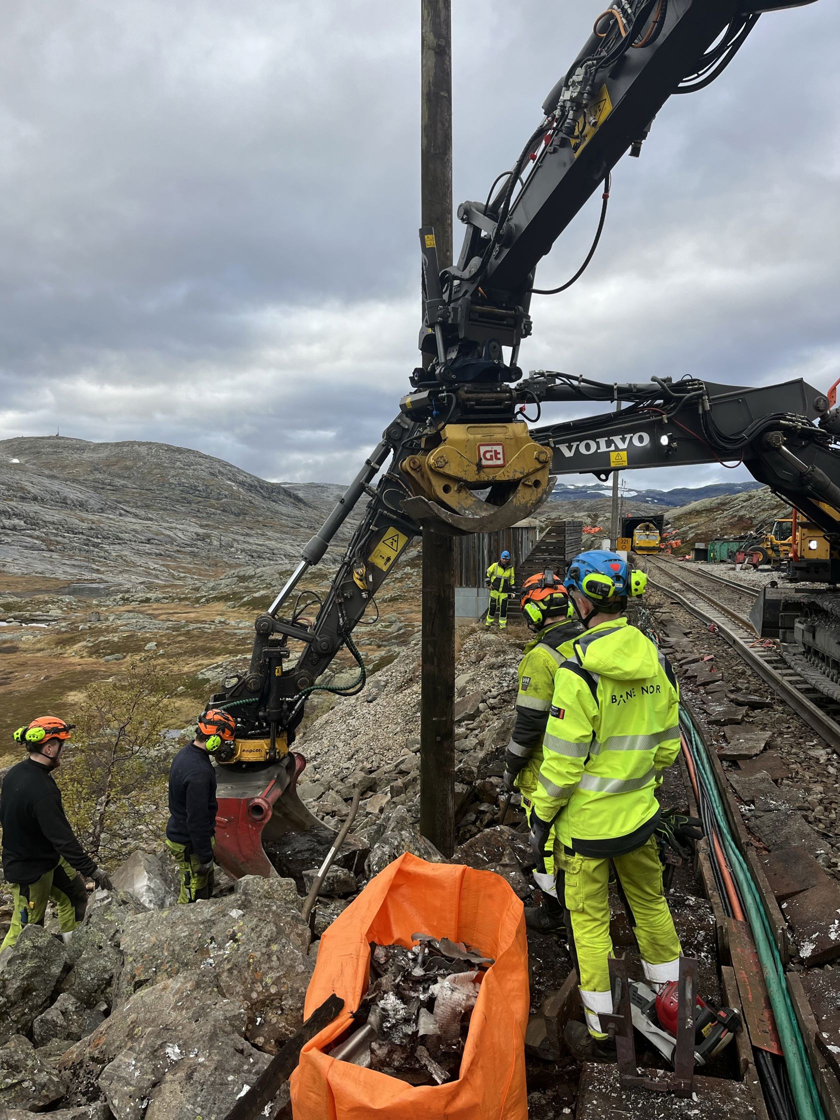 Menn i gult og oransje arbeidstøy jobber ved jernbanesporet