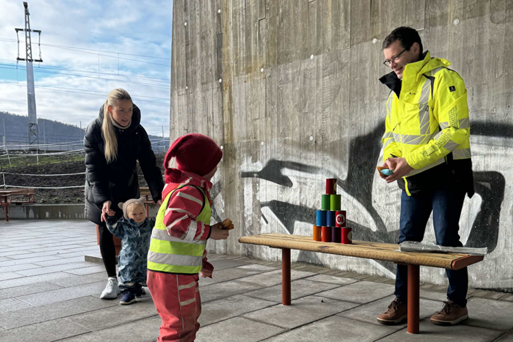 Blikkbokser oppstilt i pyramide og et barn som kaster en ertepose på det