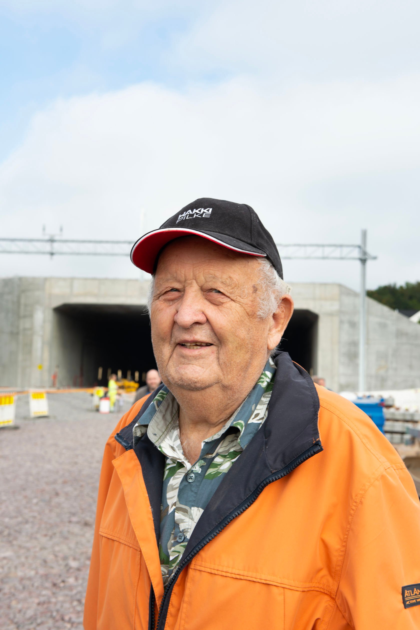 Eldre mann med oransje jakke og svart cap