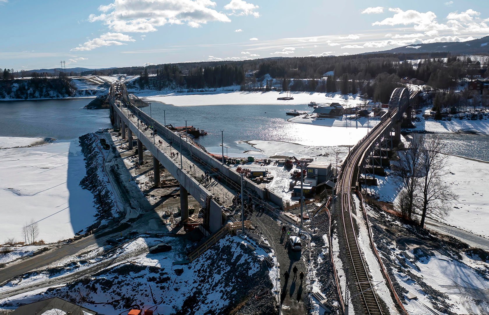 Dronefoto tatt fra Langset med gammel og ny jernbanebru, tatt under åpen dag med mange mennesker på nybrua.