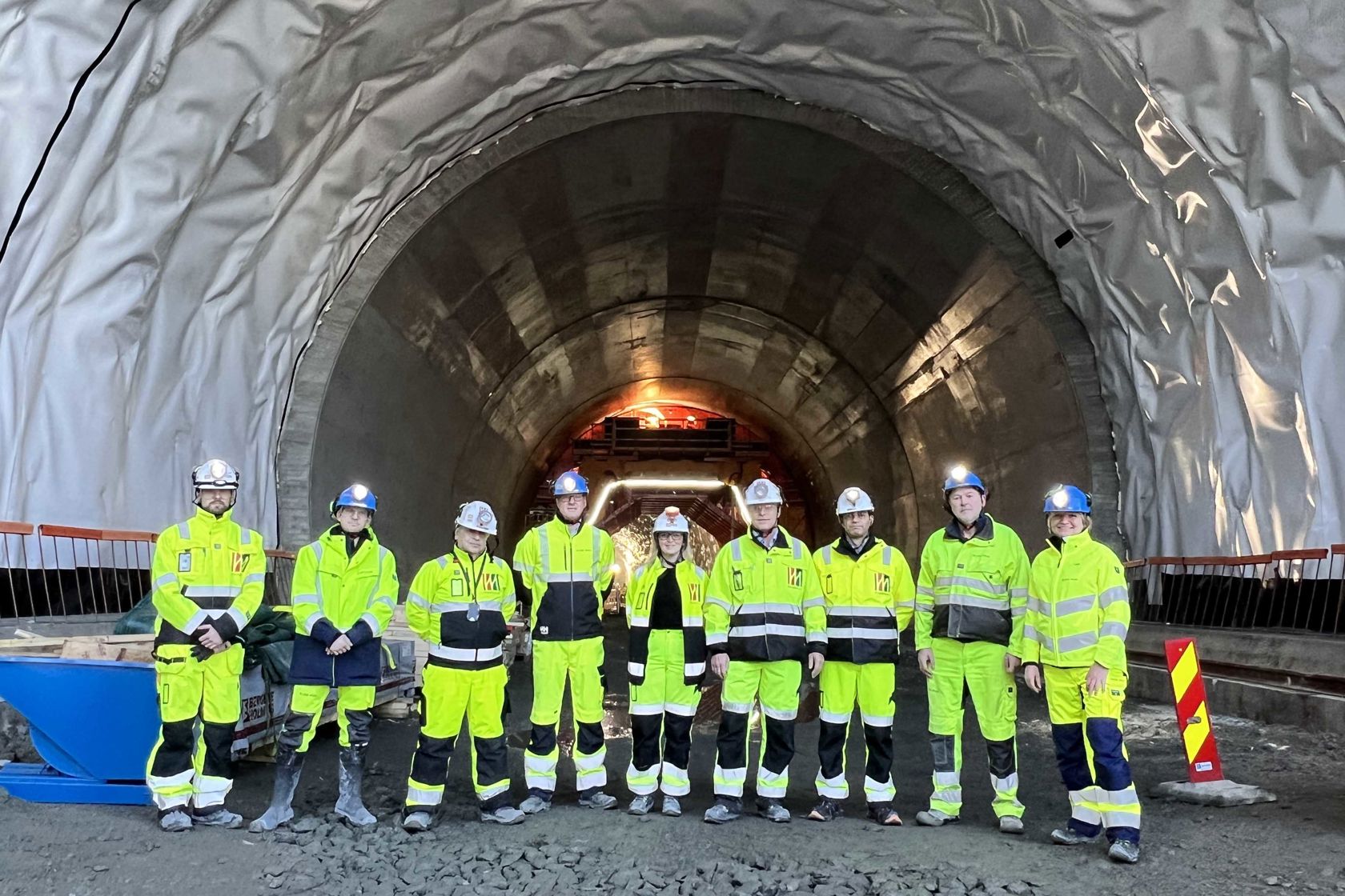 Kvinner og menn i vernetøy står oppstilt utenfor tunnel.